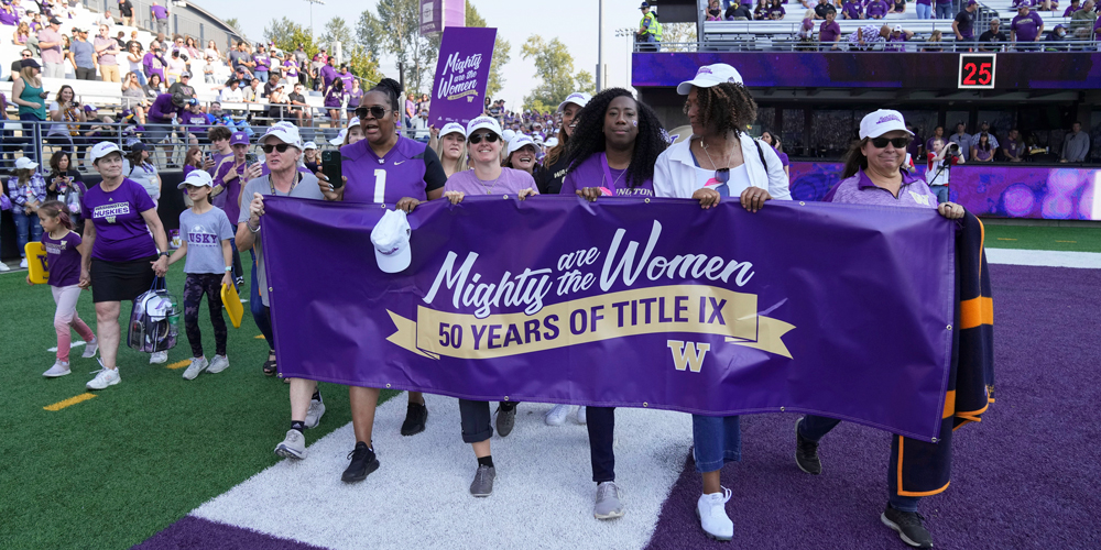 Alumni holding Mighty are the Women banner