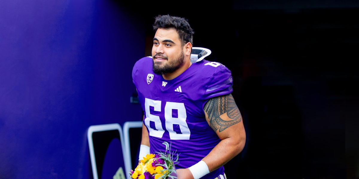 Ulumoo running out of the tunnel in Football uniform, holding flowers for senior day