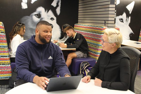 Football's Elinneus Davis talking with academic staff 