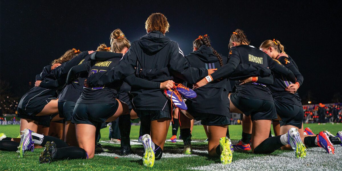 Women's Soccer team, wearing Mia Hamant jerseys, kneel together before their match