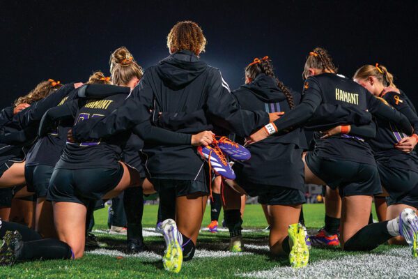 Women's Soccer team, wearing Mia Hamant jerseys, kneel together before their match