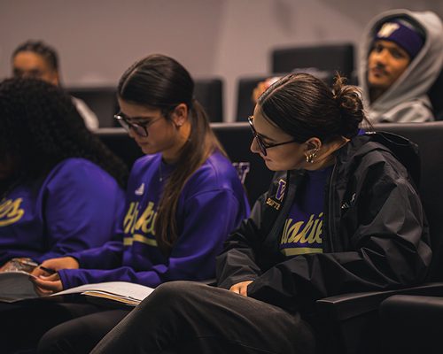 Student-athletes take notes during a financial education workshop